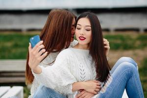 Zwei Mädchen machen Selfie auf der Bank foto