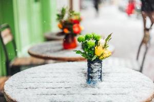 Blumen stehen auf einem verschneiten Tisch foto