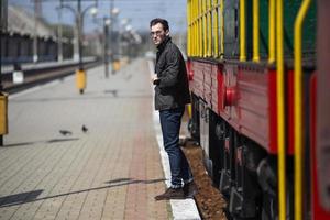 Ein Mann in Jeans im Hintergrund des Zuges und des Bahnhofs foto