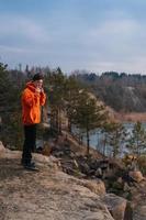 Ein junger Mann, der am Rand einer Klippe steht, posiert für die Kamera foto