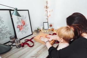 mutter und kleiner sohn packen ein geschenk foto