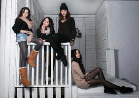 Vier stylische Models posieren auf dem Zaun sitzend. Weihnachtshintergrund foto
