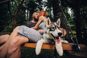 schönes paar zusammen mit hund auf einer schaukel foto