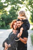 glückliche eltern mit einer kleinen tochter, die auf den schultern sitzt foto