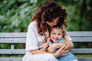 Schöne junge Mutter und Tochter an sonnigen Tagen, glückliche Familie foto