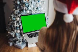 Frau mit Weihnachtsmütze, während sie mit einem Online-Freund auf dem Laptop spricht foto