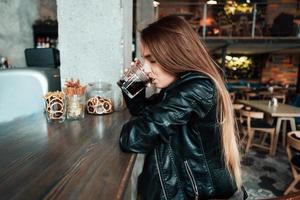 schönes Mädchen in einer schwarzen Jacke in einem Café foto