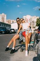 Zwei junge Mädchen mit Sonnenbrille posieren für die Kamera auf dem Parkplatz. foto