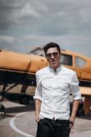 ein Mann, der auf dem Hintergrund eines kleinen einmotorigen Flugzeugs steht. foto