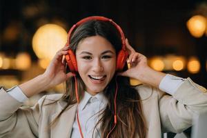 junge frau mit kopfhörern hört musik, während sie in cafés sitzt foto