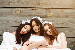 Drei charmante Mädchen in der Nähe eines Holzhauses foto
