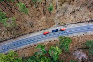 Mehrere Autos mit Kajaks auf dem Dachträger fahren auf der Straße zwischen Bäumen foto