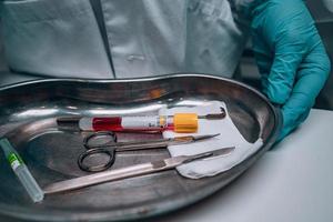 Krankenschwester in Gummihandschuhen, die ein Tablett mit chirurgischen medizinischen Geräten hält foto