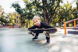 kleiner Junge, der versucht, ein Skateboard aufzuheben foto