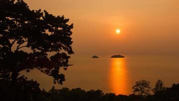 Natürliche Silhouette eines Meerblicks bei Sonnenuntergang mit Bäumen, die in Orangetönen eingerahmt sind, niemand, Kopierraum. foto