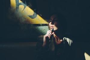 Mädchen sitzt und raucht elektronische Zigarette foto