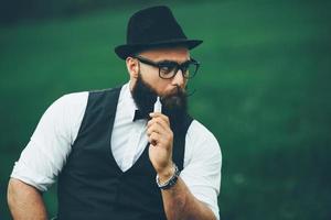 Mann mit Bart raucht elektronische Zigarette foto