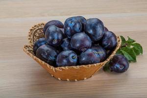 frische Pflaumen in einem Korb auf Holzhintergrund foto