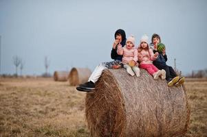 vier kinder mit früchten in den händen sitzen auf heuhahn auf dem feld. foto