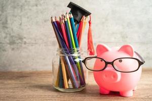 tragende Brille der Sparschweine mit bunten Bleistiften Sparbank-Bildungskonzept. foto