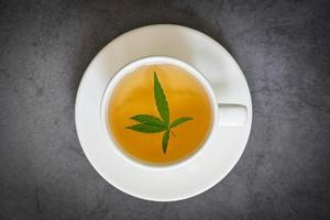 Cannabistee Kräuter auf Teetasse mit Cannabisblatt Marihuanablätter Kraut, Gesundheitstee mit Hanfblattpflanze thc cbd Kräuter Lebensmittel und Medizin foto