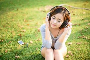 junges mädchen, das musik mit kopfhörern im stadtpark hört foto
