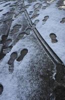 Fußspuren im schmelzenden Schnee auf dem Boden in einer Fußgängerzone foto