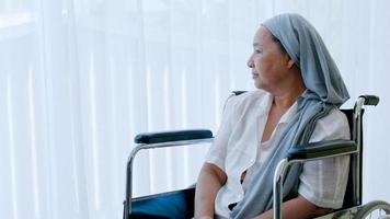 Eine ältere Frau mit Krebs sitzt im Rollstuhl und schaut aus dem Fenster, während sie ins Krankenhaus eingeliefert wird. foto