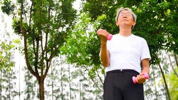 asiatischer mann, der übung macht, indem er hanteln im park anhebt. foto