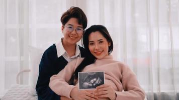 schwangere asiatische lesbische frau und ihr partner verbringen gerne zeit zusammen zu hause. foto