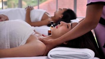 Der Massagetherapeut massiert die Schulter einer jungen Asiatin mit Hautpflege aus ätherischen Aromaölen im Spa-Salon. foto