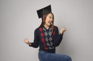 junge lächelnde frau, die abschlusshut, bildung und universitätskonzept hält foto