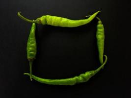 natürliche grüne Chilis auf dunklem Hintergrund. draufsicht mit lebensmittelhintergrund, schwarzer steintisch, kopierraum. foto