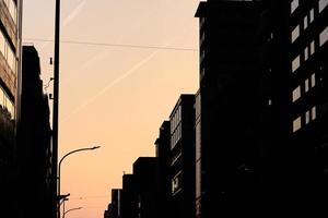 Kondensstreifen über Gebäuden in der Innenstadt als Silhouette in der Abenddämmerung foto