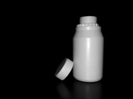 die leere weiße plastikflasche ist auf einem dunklen hintergrund. foto