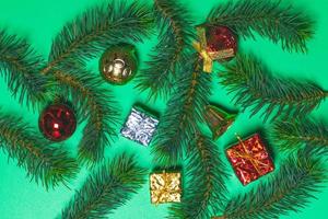 Draufsicht der Weihnachtsgeschenkbox rote Kugeln mit Fichtenzweigen und Glocke auf grünem Hintergrund. foto