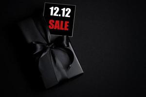 Draufsicht auf schwarze Geschenkbox mit schwarzem Hintergrund mit Kopierplatz für Text 12.12 Singles Day Sale. foto