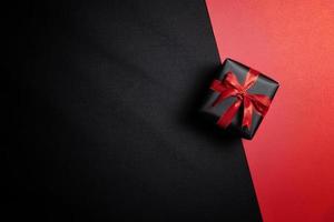 Schwarze Geschenkbox mit schwarzen Bändern isoliert auf schwarzem Hintergrund foto