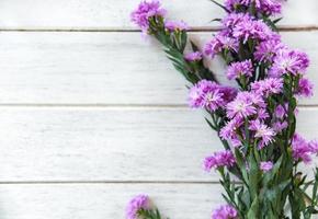 marguerite lila und statice blumenrahmen dekorieren auf weißem holzhintergrund foto