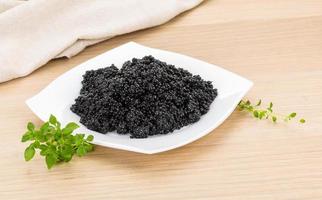 schwarzer Kaviar auf dem Teller und Holzhintergrund foto