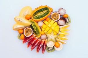 Scheiben von Starfruit, Mango, Kivano, Kiwi, Rambutan im Kreis auf weißem Hintergrund isoliert. Auswahl an frischem Obst. Blutorange. Vitamine foto