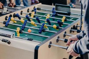 männliche Freunde verbringen unvergessliche Stunden miteinander, spielen Kicker oder Kricker, haben Spaß, wollen den Sieg erringen. Schließen Sie herauf Bild von bunten Plastikspielern foto