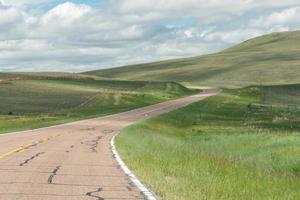 eine kurvenreiche straße durch die grünen hügel von westmontana. foto