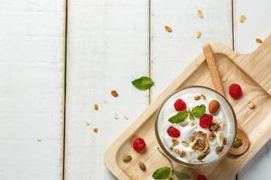 hausgemachter Joghurt oder saure Sahne in einem Glas auf dem weißen Holztisch foto