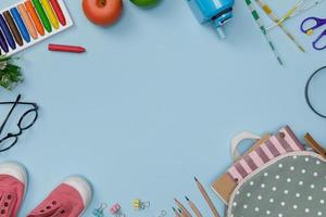 kreativer Flatlay des blauen Bildungstisches mit Schülerbüchern, Schuhen, buntem Buntstift, Brillen, leerem Raum isoliert auf blauem Hintergrund, Bildungskonzept und zurück zur Schule foto