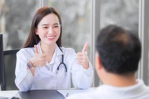 asiatische schöne ärztin lächelt und zeigt thump-up-zeichen oder sehr gut mit ihrem patienten aufgrund seiner gesundheitsversorgung im krankenhaus. foto