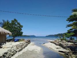 schöne aussicht, wenn der fluss unter dem blauen himmel auf das meer trifft foto