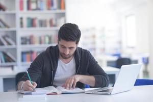 Schüler in der Schulbibliothek mit Laptop für die Recherche foto