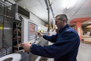 Tischler, der eine CNC-Holzbearbeitungsmaschine berechnet und programmiert foto