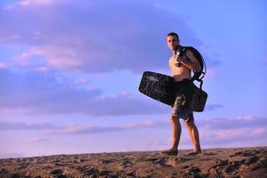 Porträt eines jungen Kitsurf-Mannes am Strand bei Sonnenuntergang foto